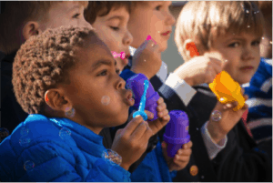 Pre-K students blow bubbles at the dedication of Noah's Garden